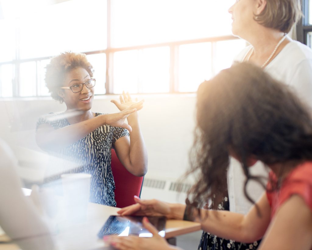 Candid picture of a female boss and business team collaborating. Filtered serie with light flares, bokeh, warm sunny tones.
